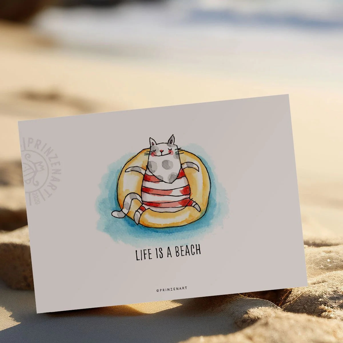 Strandkatze müsste man sein! Auf einem Schwimmring der Sonne entgegen! Postkarte: Life is a beach / Serie Strandkatze