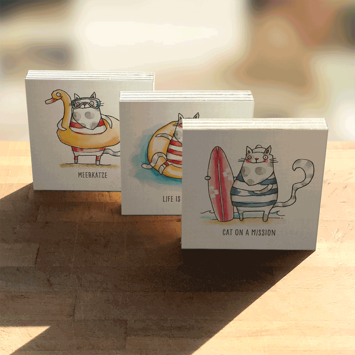 Drei Holzbilder Strandkatzen-Serie auf Holztisch: Meerkatze, Life is a Beach, Cat on a Mission | Prinzenart