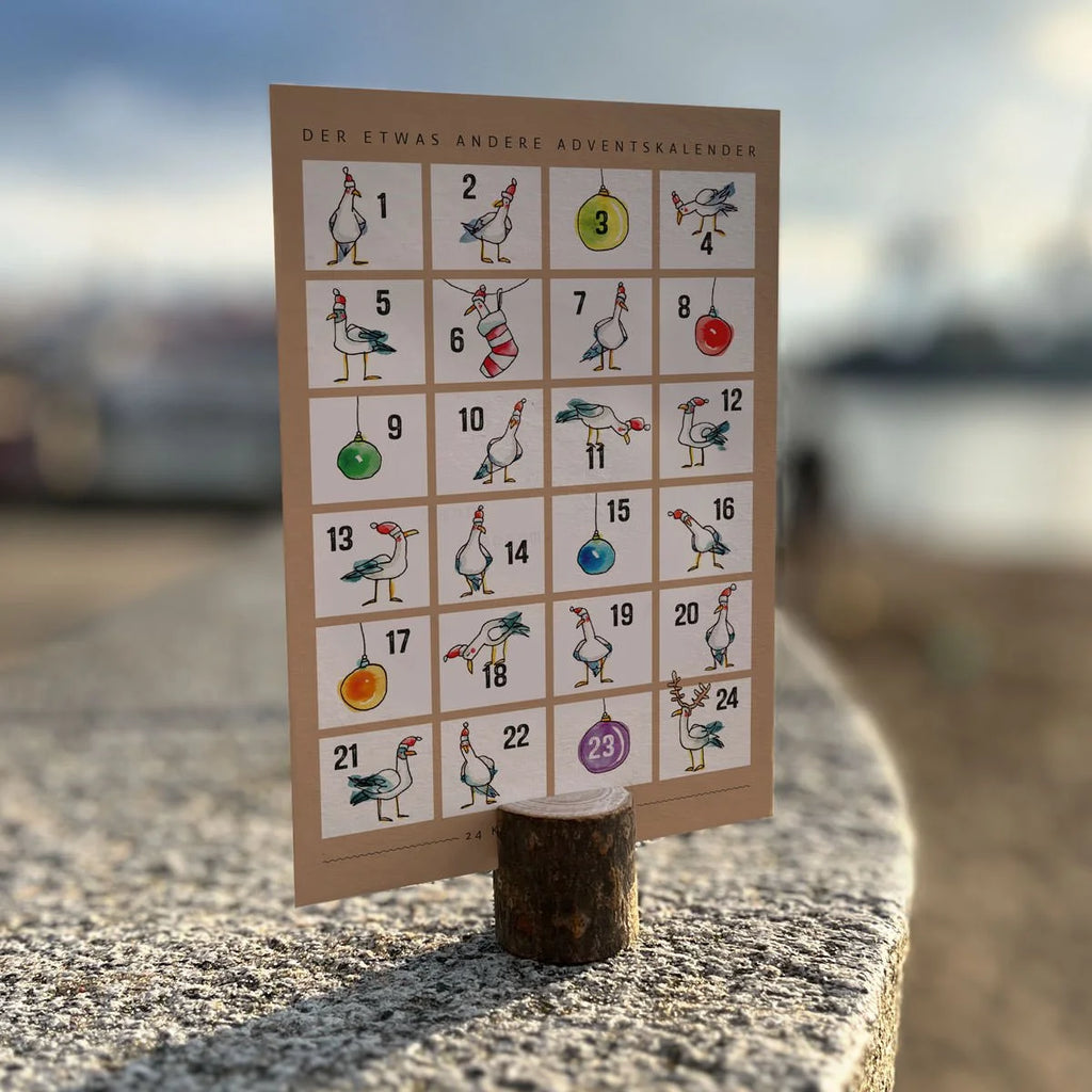 Adventskalender-Postkarte mit 24 lustigen Möwen-Illustrationen und Weihnachtskugeln auf Steinmauer | Prinzenart